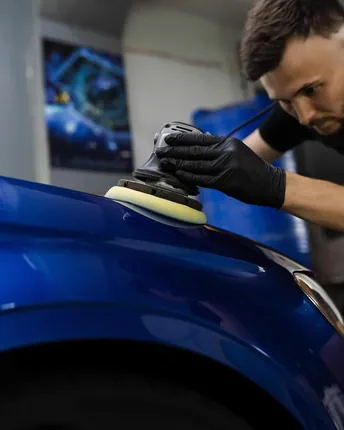 Detailing a blue car with a dual action polisher.