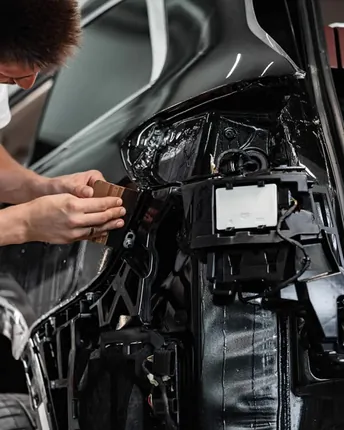 Bodywork on a dark car with a rear panel opened up.